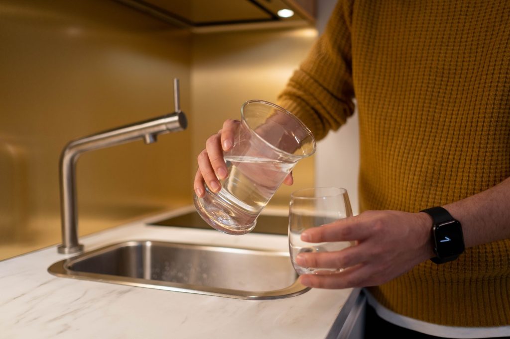 Water filter pitcher with a glass and stainless steel bottle on a kitchen counter